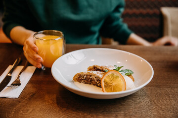 Traditional strudel with ice cream, served on a white plate at a restaurant.