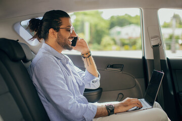 Positive arab man freelancer working online while sitting in taxi