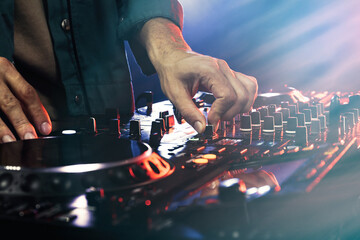 DJ creating music on modern console mixer in night club, closeup