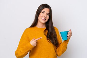 Young Brazilian woman holding cup of coffee isolated on white background and pointing it