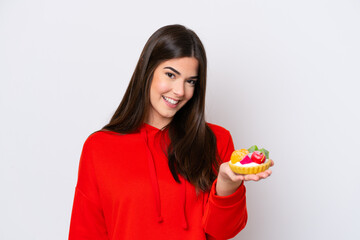 Young Brazilian woman holding a tartlet isolated on white background with happy expression