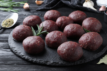 Many fresh raw meatballs on black wooden table, closeup