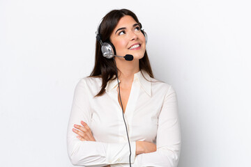 Telemarketer caucasian woman working with a headset isolated on white background looking up while...