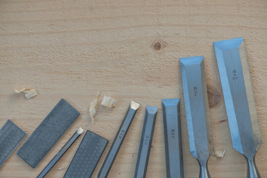 Various carpentry chisels and sharpening stones on wooden background.