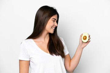Young Brazilian woman holding an avocado isolated on white background with happy expression