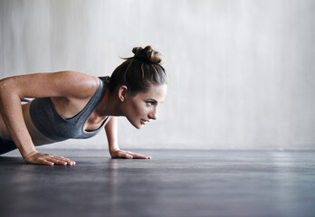 Fototapeta na wymiar Pushing the limits. Shot of a woman doing push-ups at the gym.