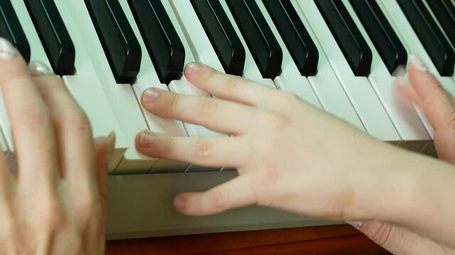 Close-up of a woman's and a child's hands playing the piano. Family leisure playing a musical instrument. Mom and son play the piano. Creativity family.selective focus