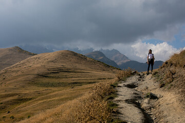 Portrait of a happy young woman travel with small backpack hiking in mountains