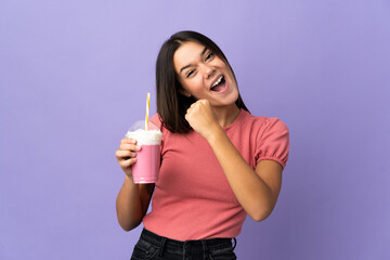 Teenager girl holding a strawberry milkshake celebrating a victory