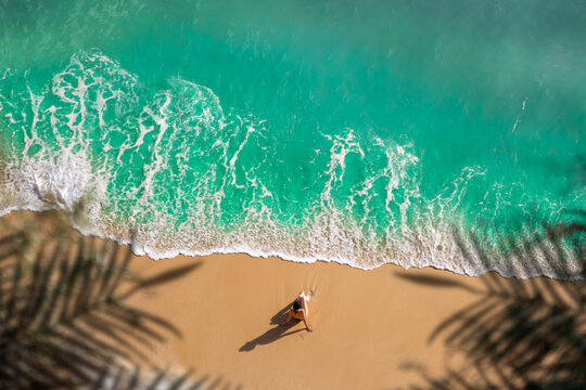 aerial view of woman sitting on golden sand beach with turquoise sea - Algarve, Portugal