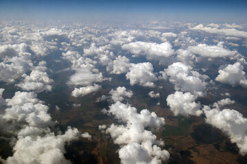 Aerial view from airplane window of white puffy clouds on bright sunny day