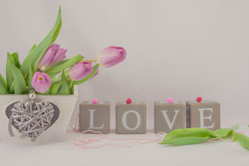 Walentynkowe tło, różowe tulipany w pudełku drewnianym z serduszkiem i napis z brył drewnianych układające się w sowo love. - obrazy, fototapety, plakaty