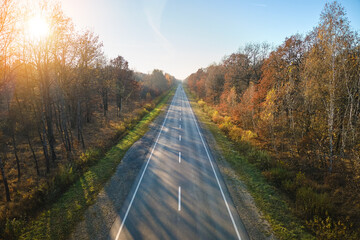 Aerial view of empty intercity road between autumn woods at sunset. Top view from drone of highway in evening