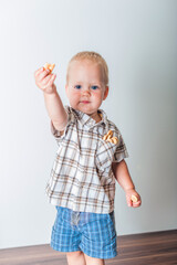 Toddler boy in blue shorts and shirt eating cookies close-up and copy space..