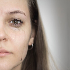 A girl with leaking mascara from tears. The girl is crying. Close up. Isolated