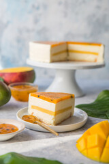 Cheese cake with mango fruit on a grey background. Cheesecake with passion fruit sauce on top, decorated with berries and fruits