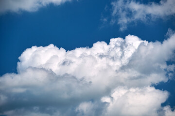 Naklejka na ściany i meble Bright landscape of white puffy cumulus clouds on blue clear sky