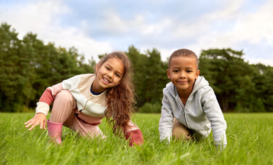 Fototapeta premium childhood, leisure and people concept - happy smiling little boy and girl having fun at park