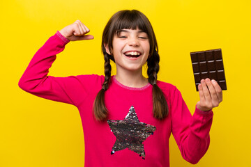 Little caucasian girl with chocolat isolated on yellow background doing strong gesture