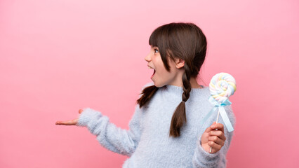 Little caucasian girl holding a lollipop with surprise expression while looking side