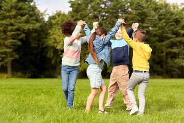 Fototapeta premium childhood, leisure and people concept - group of happy kids playing round dance at park