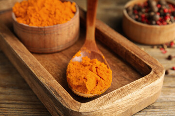 Spoon and bowl with saffron powder on wooden table, closeup