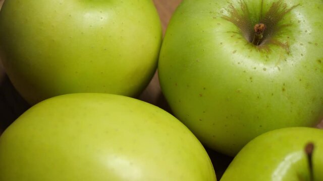 Four apples of the Reinette Simirenko variety on a wooden surface, close-up. Rotating fruits.
