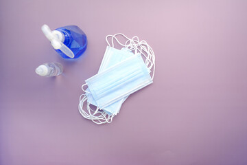 Surgical masks, and hand sanitizer on purple background 