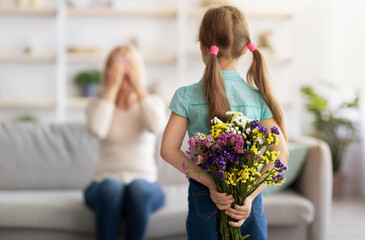 Back view of little girl greeting woman with flowers