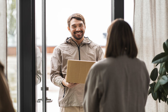 shipping, transportation and people concept - delivery man with parcel box and customer at home