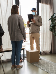 health protection, mail service and pandemic concept - delivery man in face protective mask with parcel box and tablet pc computer and female customer at home
