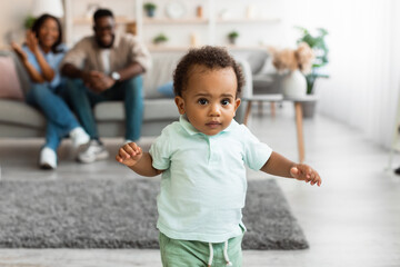 Cute baby toddler walking in living room making first steps