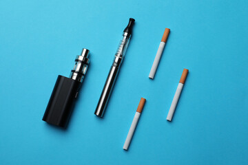 Electronic and regular cigarettes on light blue background, flat lay