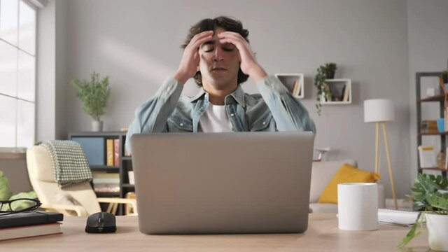 upset young arab man opens computer starts working,middle eastern male student sits at his desk using laptop gets angry and disappointed,fail issue concept