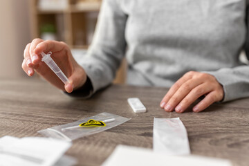 medicine, quarantine and pandemic concept - hands of woman making self testing coronavirus test and...