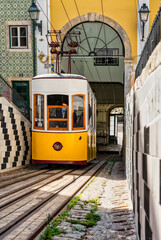 Yellow elevator going up the slope of one of the typical neighborhoods in the city of Lisbon in...