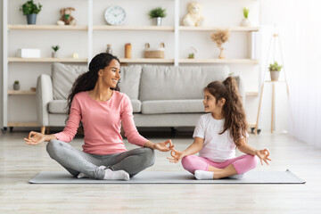Fototapeta na wymiar Cheerful mother and daughter meditating together at home