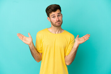 Young caucasian handsome man isolated on blue background making doubts gesture