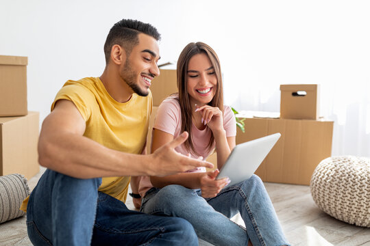 Cheerful multiracial couple with tablet computer browsing web to buy household goods for new home - Powered by Adobe