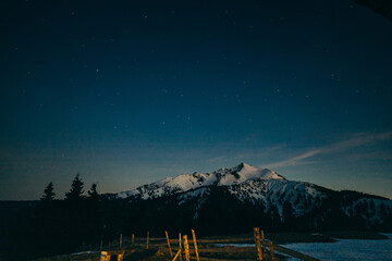 Snowy meadow, snowy mountains and stars in the background