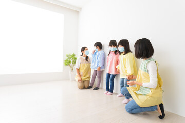 Fototapeta premium マスクを付けて幼稚園で遊ぶ子どもたちの先生