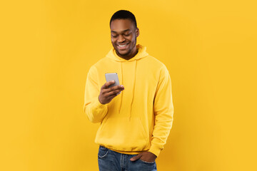 African American Guy Using Cellphone Texting Standing Over Yellow Background