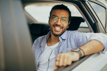 Stylish arab guy travelling by car service, listening to music