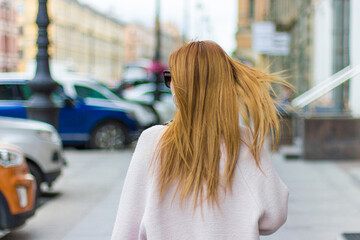 a girl with flowing hair walks along a city street