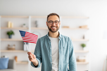 Handsome young guy holding American flag and smiling at camera indoors. Abroad education and...