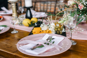 A beautiful outdoor wedding setting in pink flowers. plates and cutlery on a wooden table against a backdrop of greenery. On a Summer day 
a wooden reception table in the backyard, decorated with rose