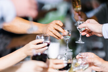 Glasses filled with alcohol and juice. toast at a party. Hands holding wine glasses on a table.  People clinking wine glasses.