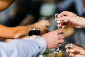 Glasses filled with alcohol and juice. toast at a party. Hands holding wine glasses on a table.  People clinking wine glasses.