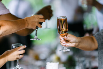 Glasses filled with alcohol and juice. toast at a party. Hands holding wine glasses on a table.  People clinking wine glasses.