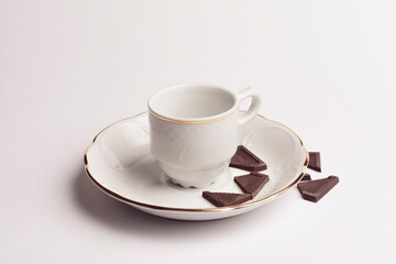 white cup with pieces of chocolate on white background